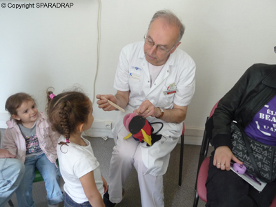 Le médecin anesthésiste montre comment se passe l'examen de la bouche à l'aide de la peluche en forme de poisson